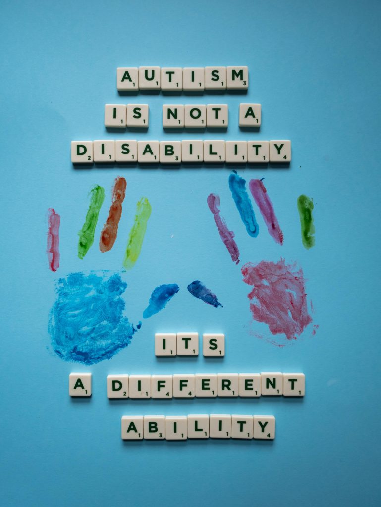 Creative composition with Scrabble tiles and paint promoting autism awareness and acceptance.